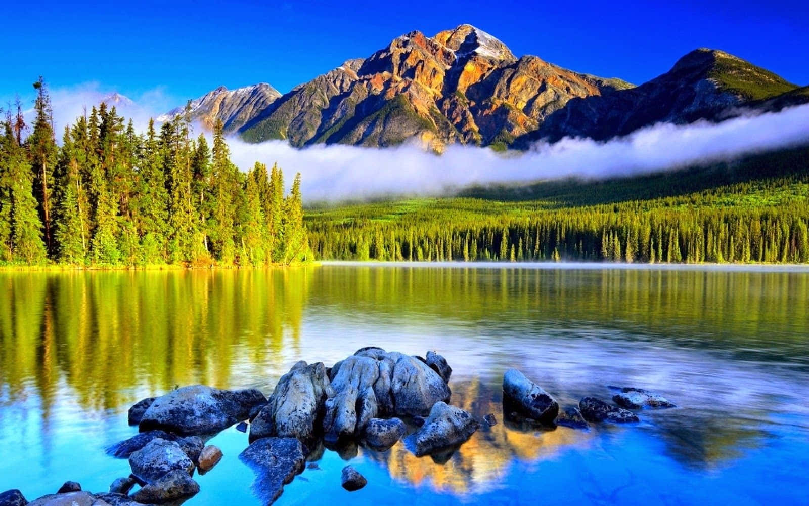 寧靜的山湖，森林倒影，霧氣籠罩的山峰，天空清澈湛藍。
