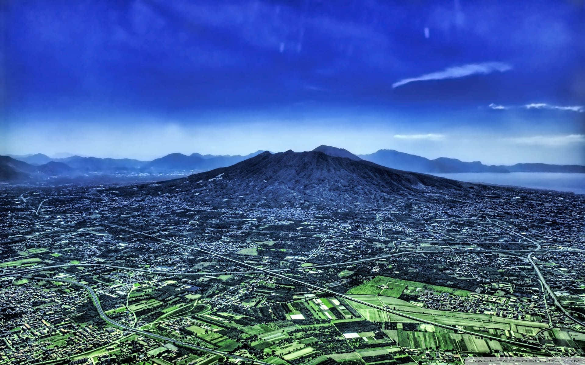 城市在巨大火山腳下延伸，天空深藍。