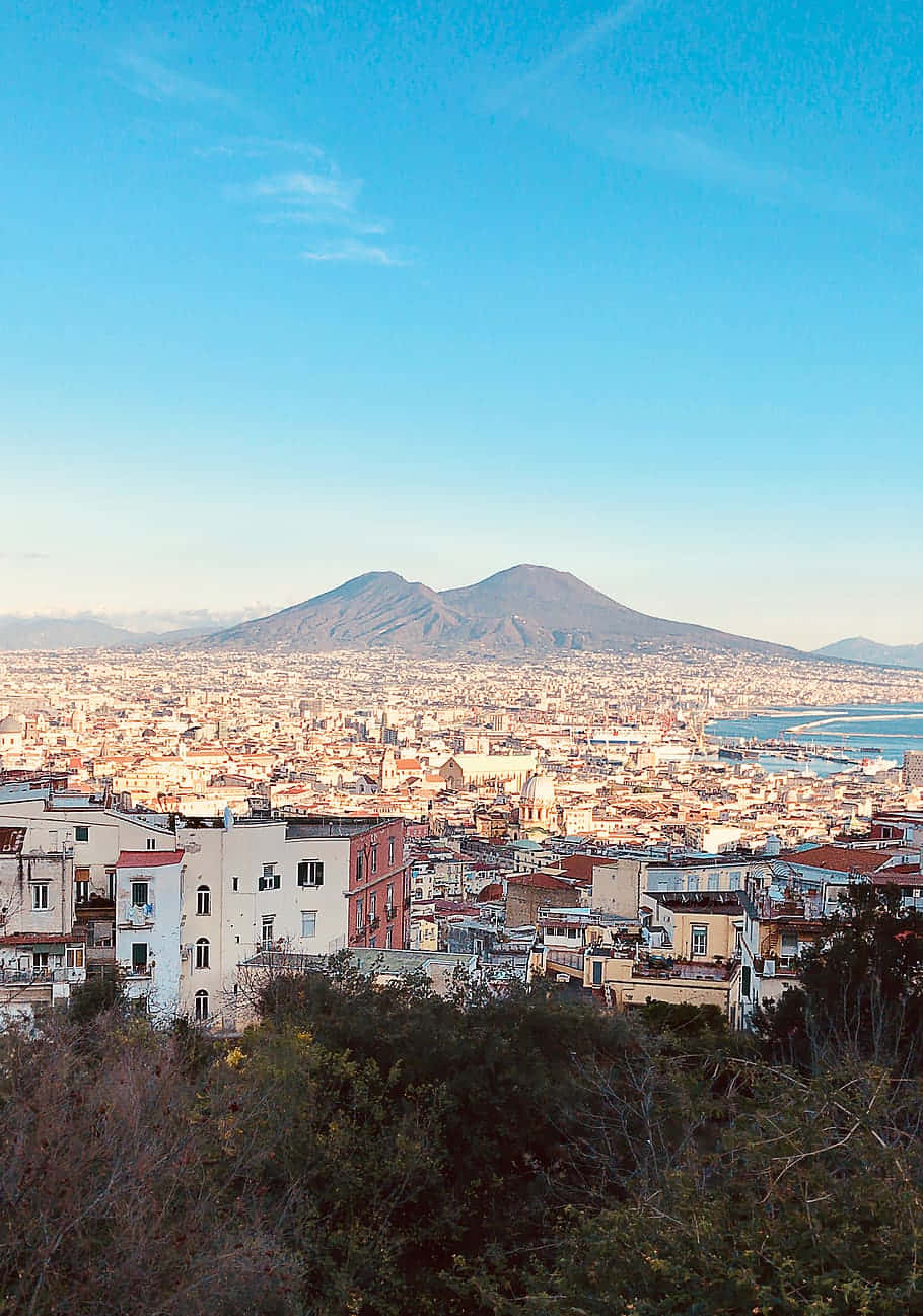 拿坡里城市景觀，背景為日落時分的維蘇威火山。