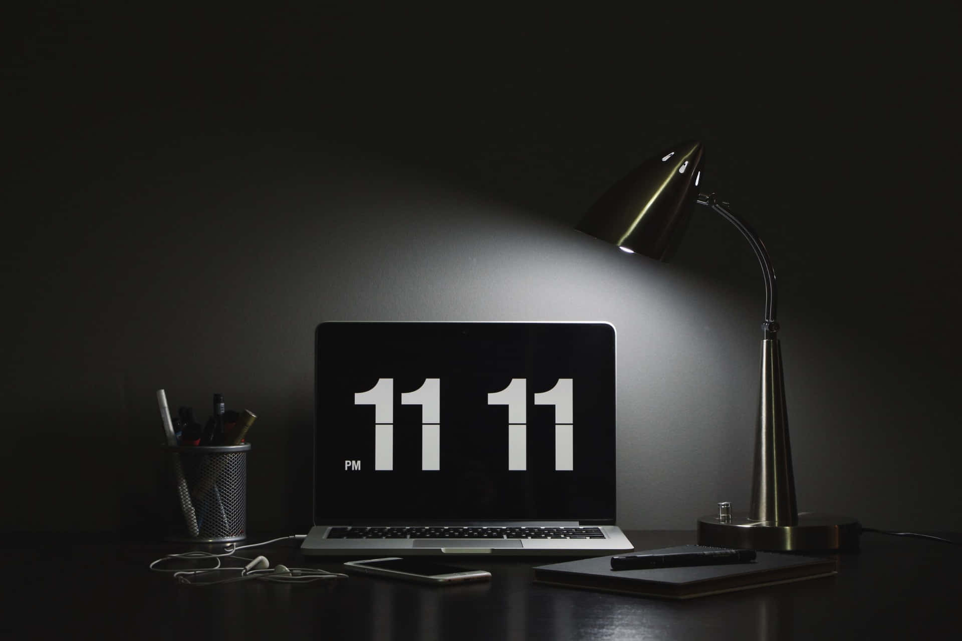 筆記型電腦顯示 11 11 PM，被枱燈照亮，在黑暗的房間中。