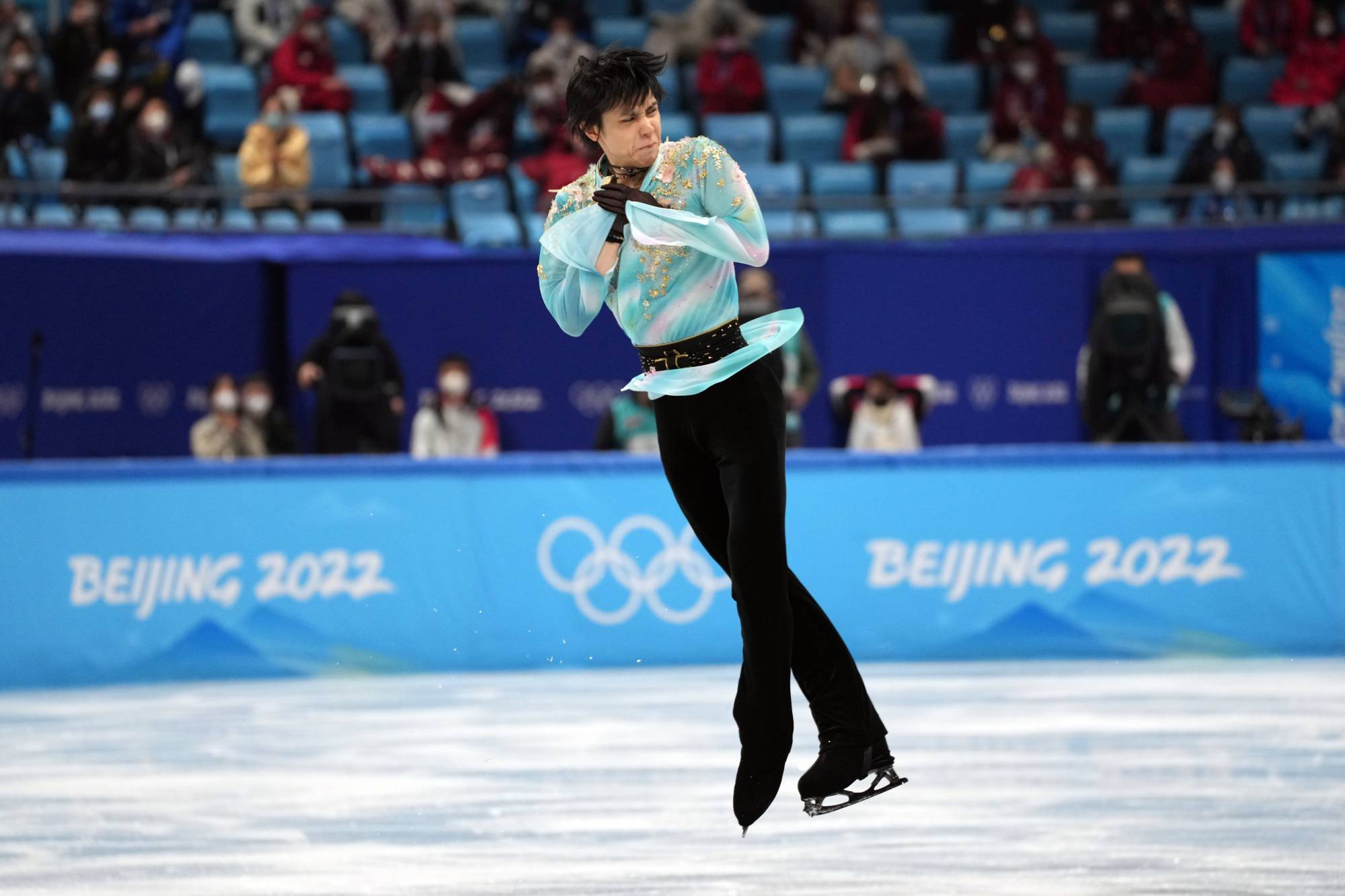 羽生結弦2022冬季奧運會 壁紙 — 一位身穿淺藍色刺繡服裝的男性花樣滑冰運動員在北京2022年冬奧會期間在冰場上空跳躍。
