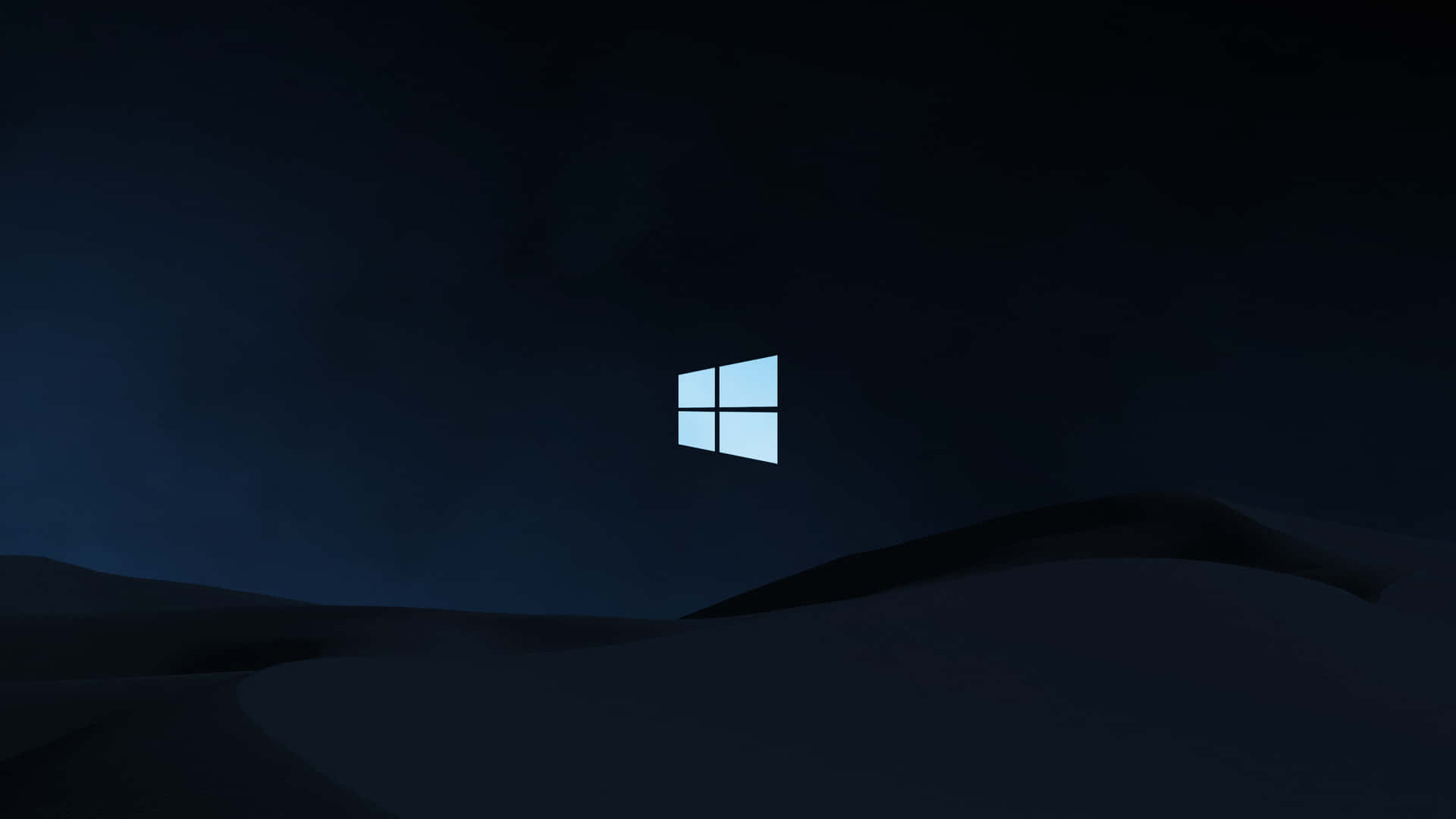 夜間發光的Windows標誌在黑暗山丘上方