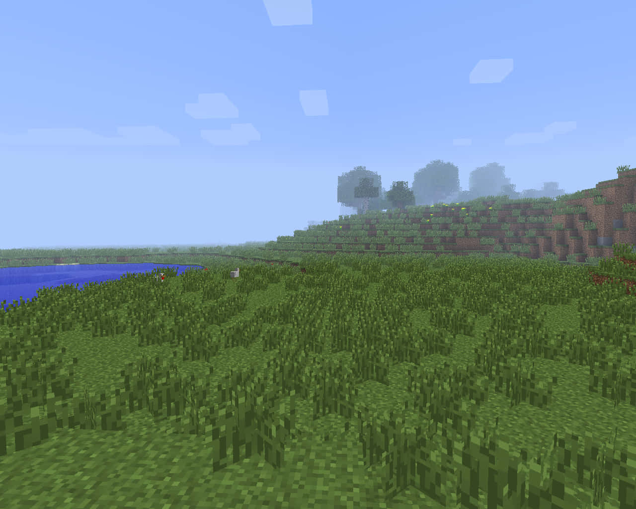翡翠綠天空與金色陽光下的Minecraft草地 壁紙 — 一個方塊狀的Minecraft景觀，有綠色草山丘、藍色河流和遠處的樹木，天空晴朗。