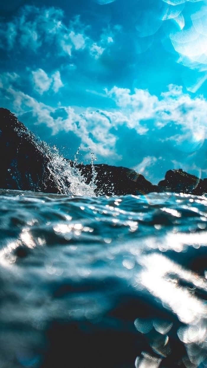 在明亮的藍天白雲下，海浪拍打黑色岩石。