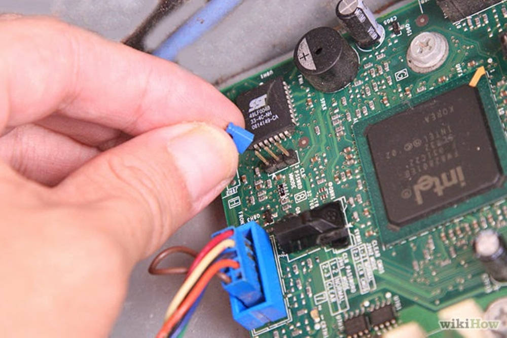 手將藍色電纜連接到帶有Intel晶片的綠色電路板。