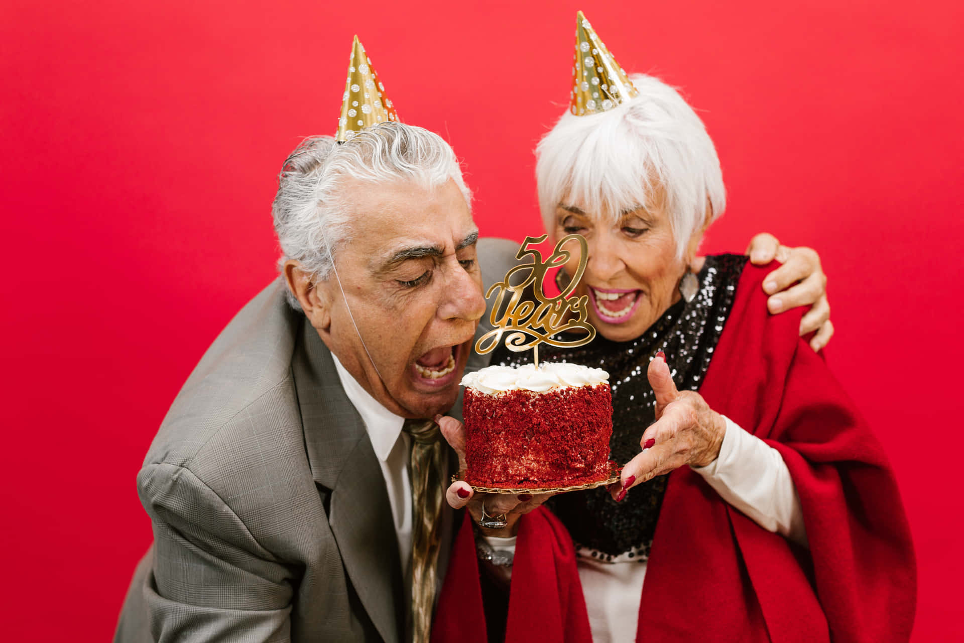 老年夫婦以紅絲絨蛋糕和派對帽慶祝50週年。