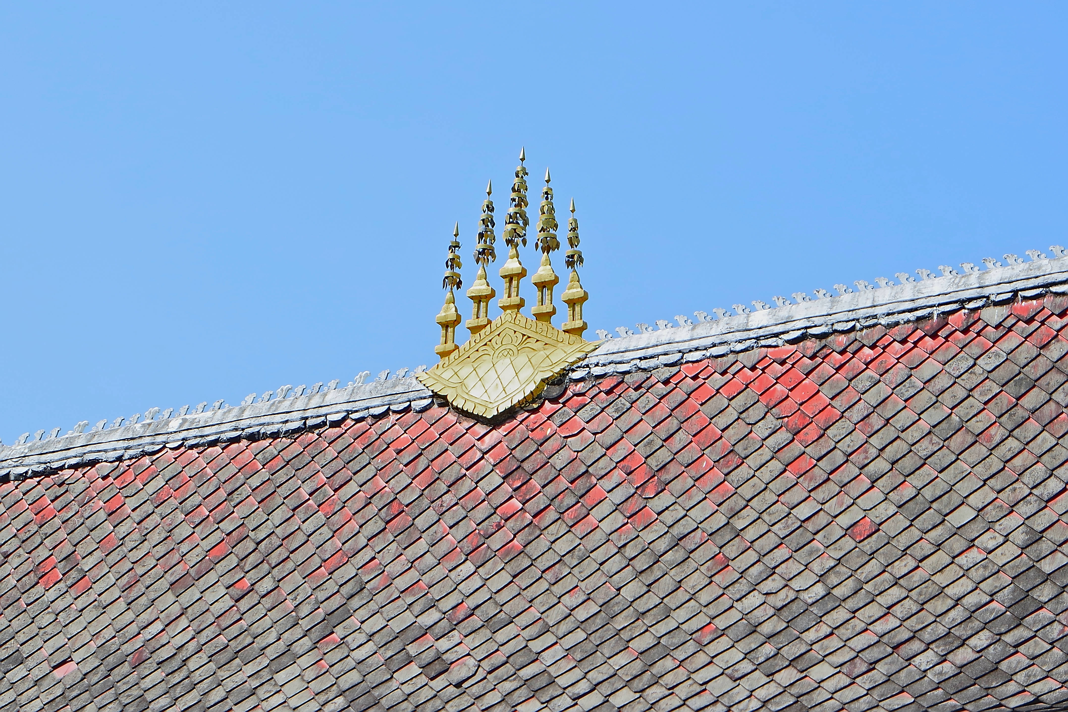 老撾琅勃拉邦瓦特阿哈姆寺 壁紙 — 金色華麗的屋頂飾物在清澈的藍天下，為傳統瓦片屋頂加冕。
