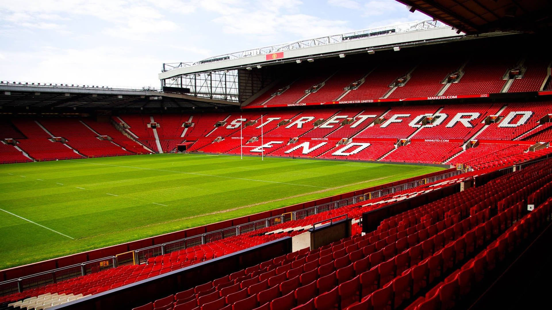 空蕩的足球場，設有紅色座位和 'Stretford End' 標牌。