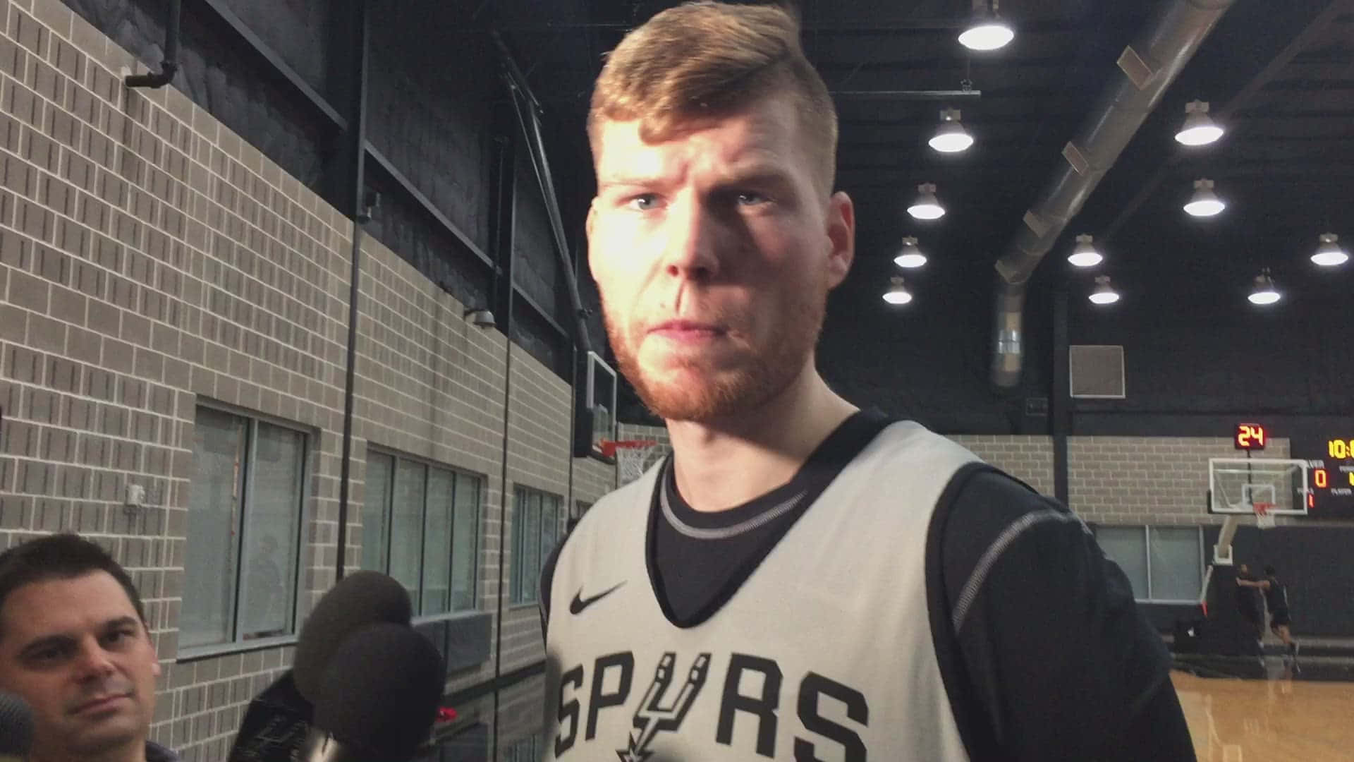 身穿Spurs球衣的籃球運動員在體育館接受訪問