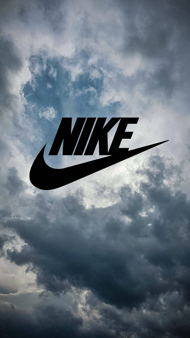 耐克勾形標誌 壁紙 — 大膽的黑色Nike標誌漂浮在充滿旋轉灰色和藍色暴風雲的戲劇性天空中。