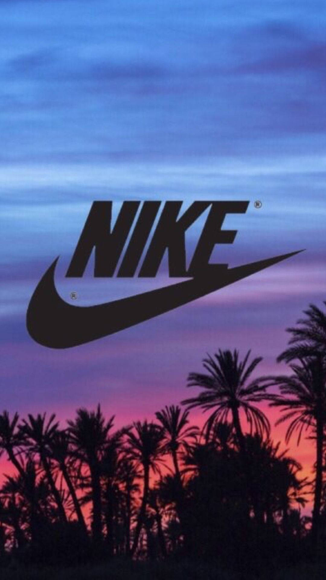 耐克女孩棕櫚樹剪影 壁紙 — Nike 標誌在充滿活力的暮色天空下以剪影呈現，下方有棕櫚樹。