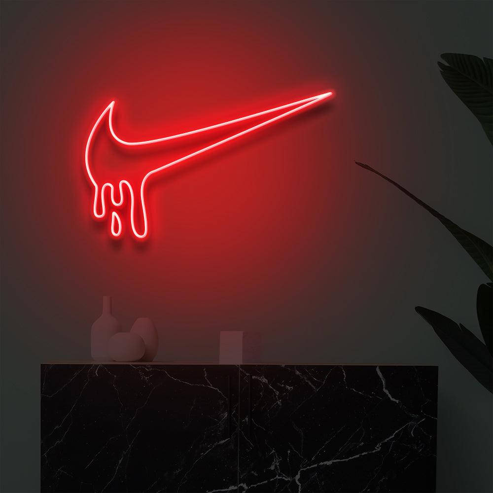 紅色霓虹燈Nike標誌滴落在黑暗牆壁上，上方是帶植物的大理石檯面。