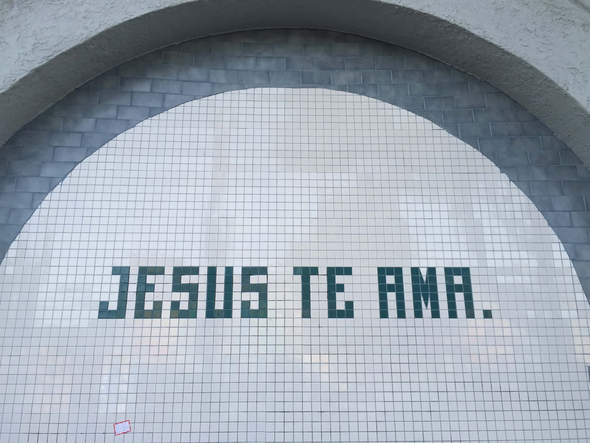 一個瓷磚拱門，上面用綠色瓷磚寫著「Jesus te ama」的信息。
