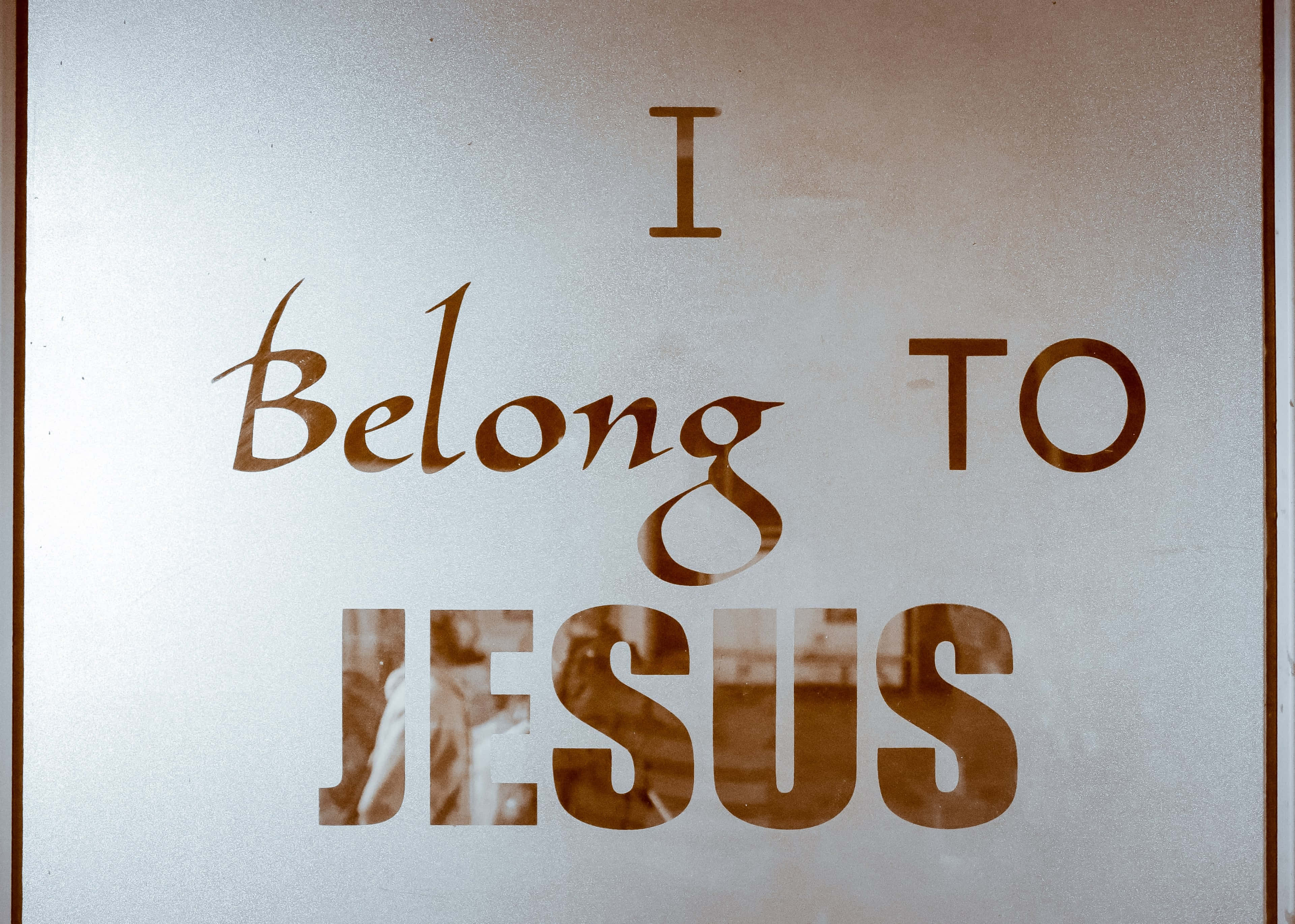 耶穌拯救 壁紙 — 一扇磨砂玻璃門上以棕色字體顯示「I Belong TO JESUS」字句，透過文字可見微弱的倒影。