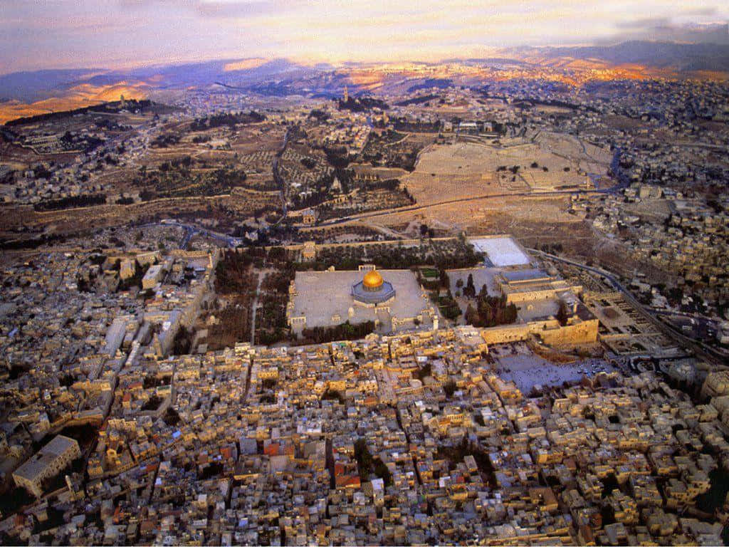 Israel 桌布 壁紙 — 耶路撒冷黃金時刻的航拍圖，圓頂清真寺在古老的石建築和廣闊的城市景觀上方閃耀。