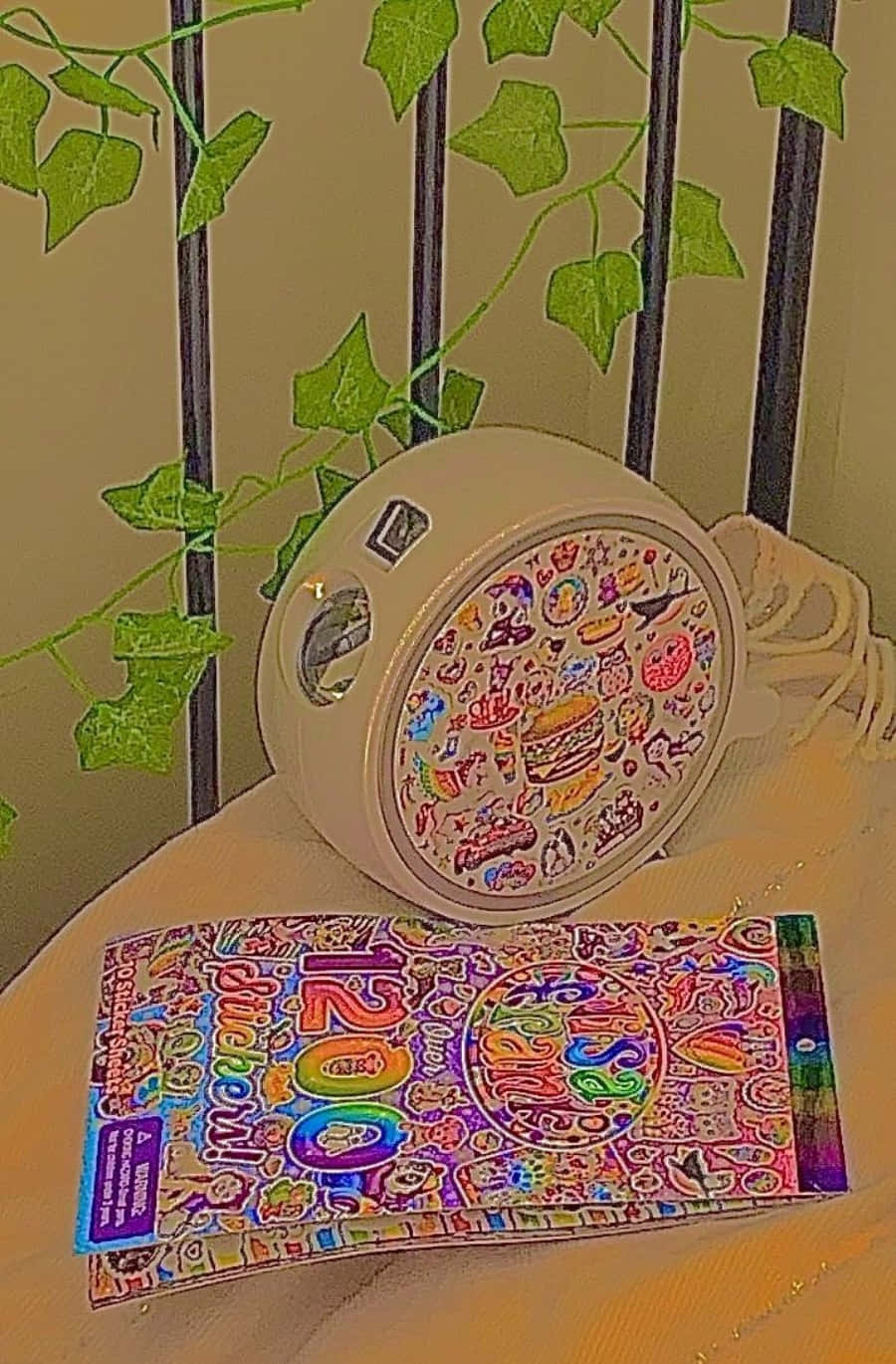 一部相機和貼紙包裝飾著鮮豔的貼紙，放在木質表面上的綠色常春藤旁邊。
