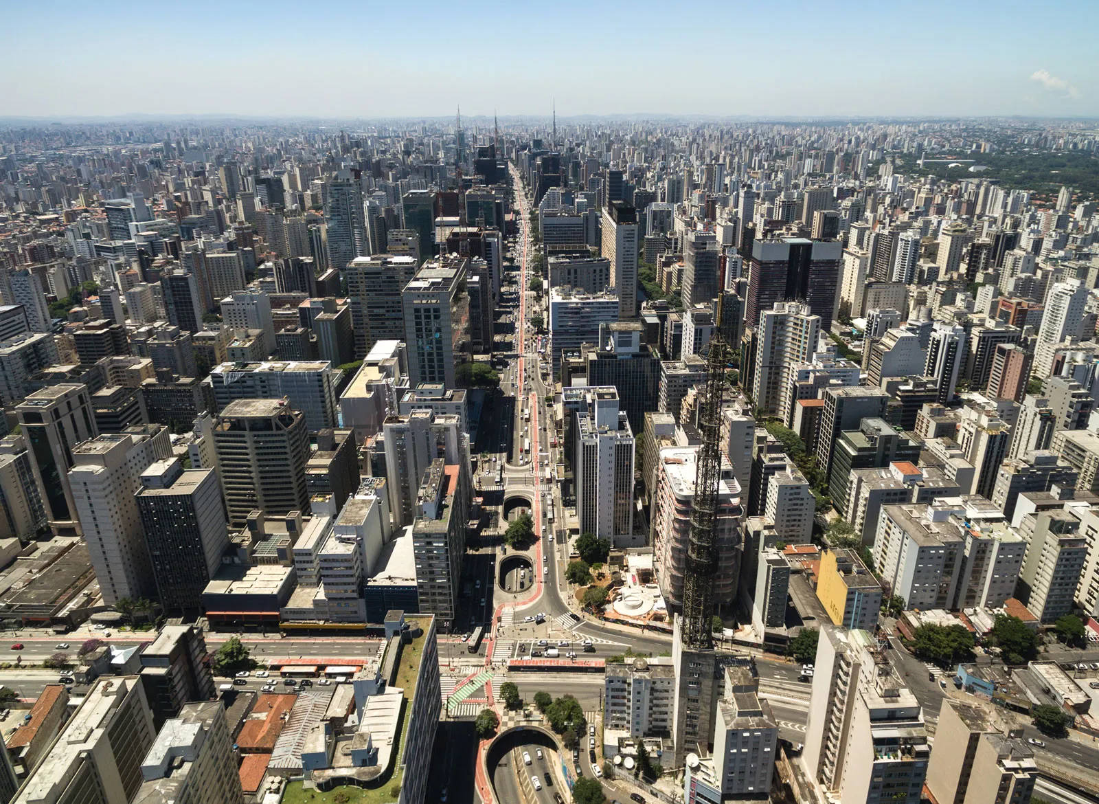 聖保羅空中城市景觀 壁紙 — 晴朗藍天下，高樓大廈密集的廣闊現代城市及中央大道的鳥瞰圖。