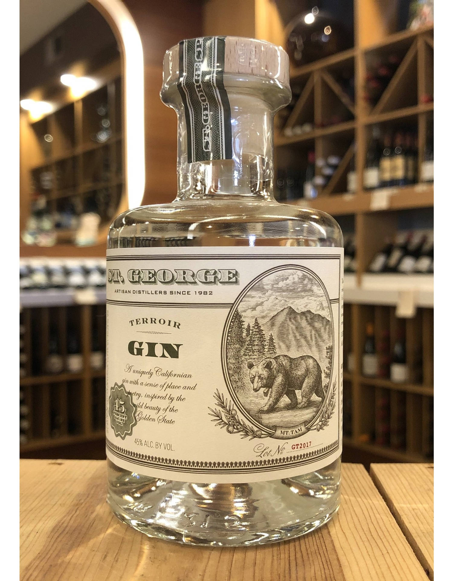 一瓶帶有熊標籤的 St George Terroir Gin 放在酒類商店的木桌上。