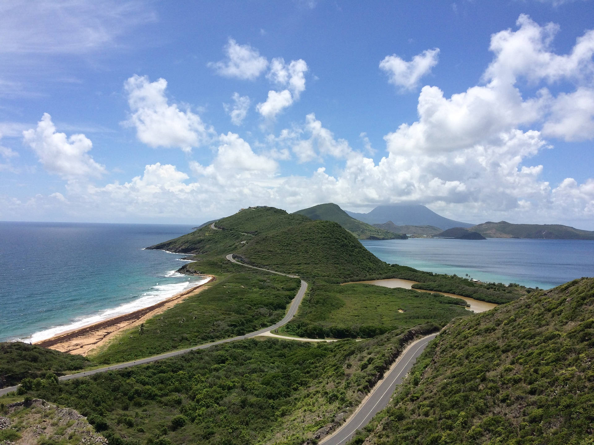 沿著風景如畫的海岸景觀蜿蜒的道路，有綠色山丘和藍色海洋。