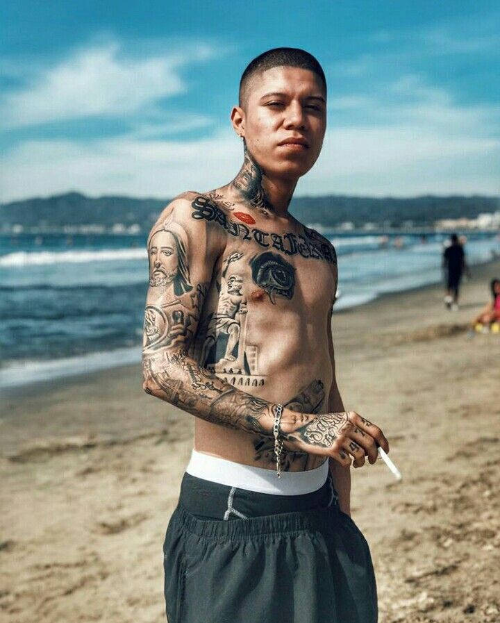 紋身男人在陽光海灘上手持香煙近海