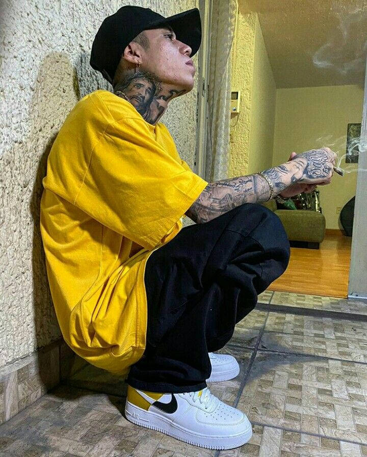 有紋身嘅男人著黃色衫喺室內踎低食煙。