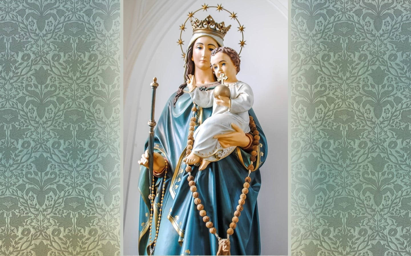 Mary 桌布 壁紙 — 聖母瑪利亞懷抱嬰兒耶穌的寧靜雕像，以華麗的藍綠色大馬士革花紋牆紙為背景。