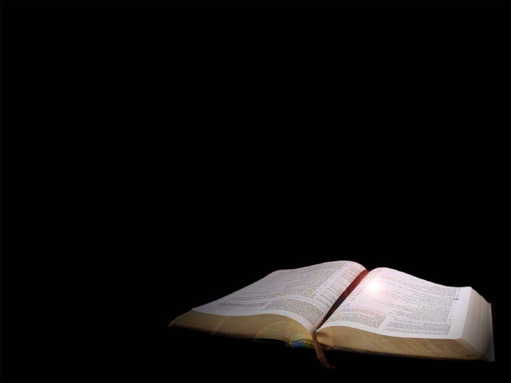一本打開的書在黑暗中發光，光線從書頁中透出。 — 聖經 壁紙