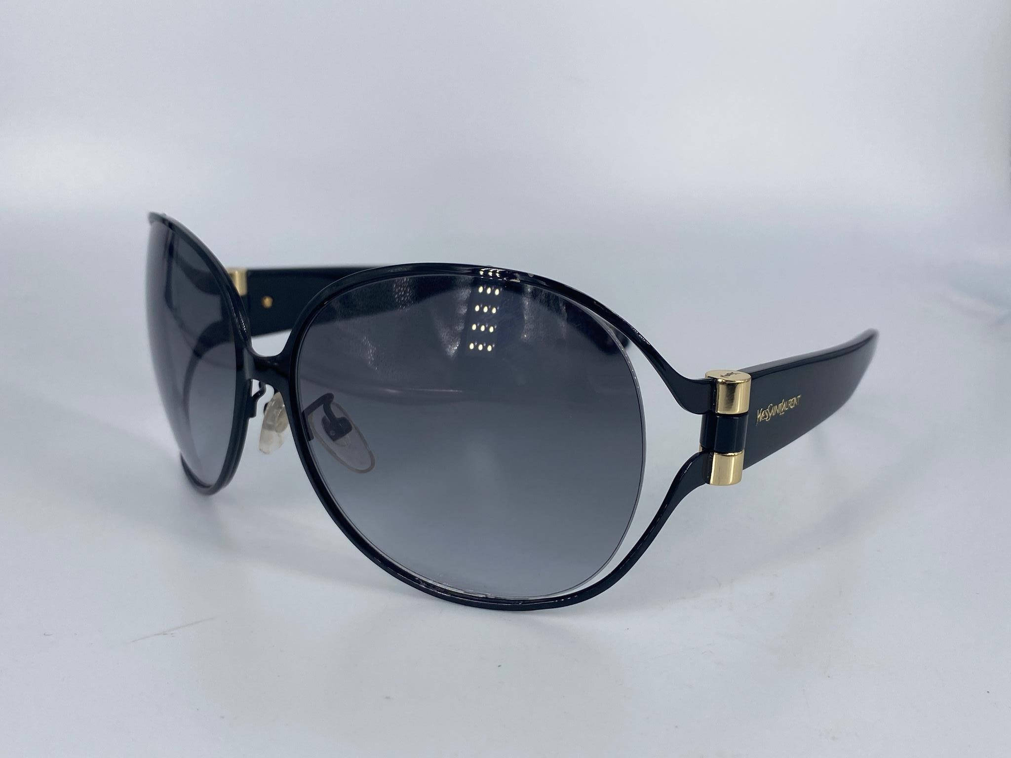 聖羅蘭YSL太陽眼鏡6199 QRI 壁紙 — 優雅的大碼黑色太陽眼鏡，帶有金色點綴和漸變鏡片，放置在純白色表面上。