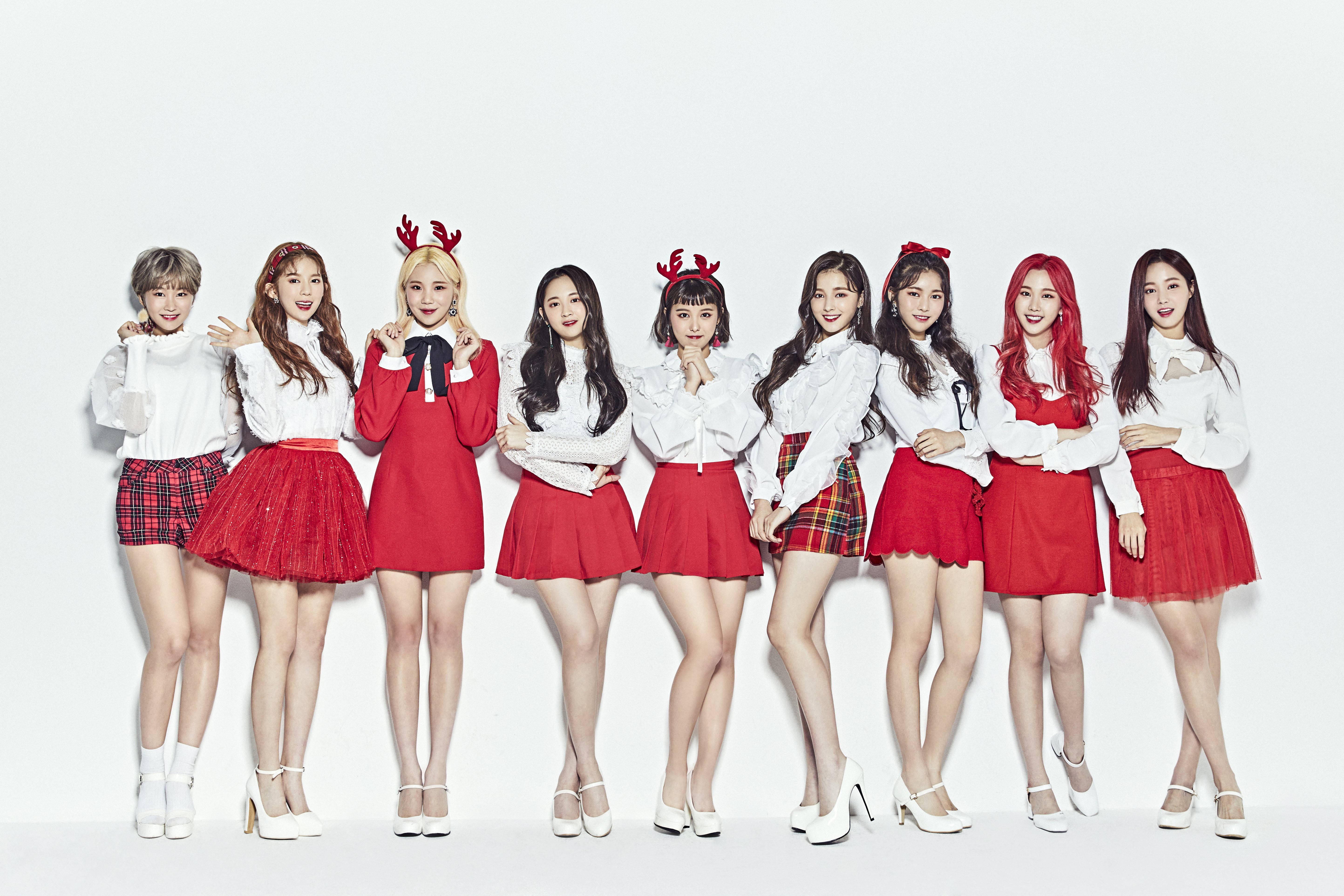 聖誕主題拍攝南西 Momoland 高畫質 壁紙 — 九位年輕女性身穿喜慶的紅白服飾，頭戴馴鹿角，在純白背景前歡樂地擺姿勢。
