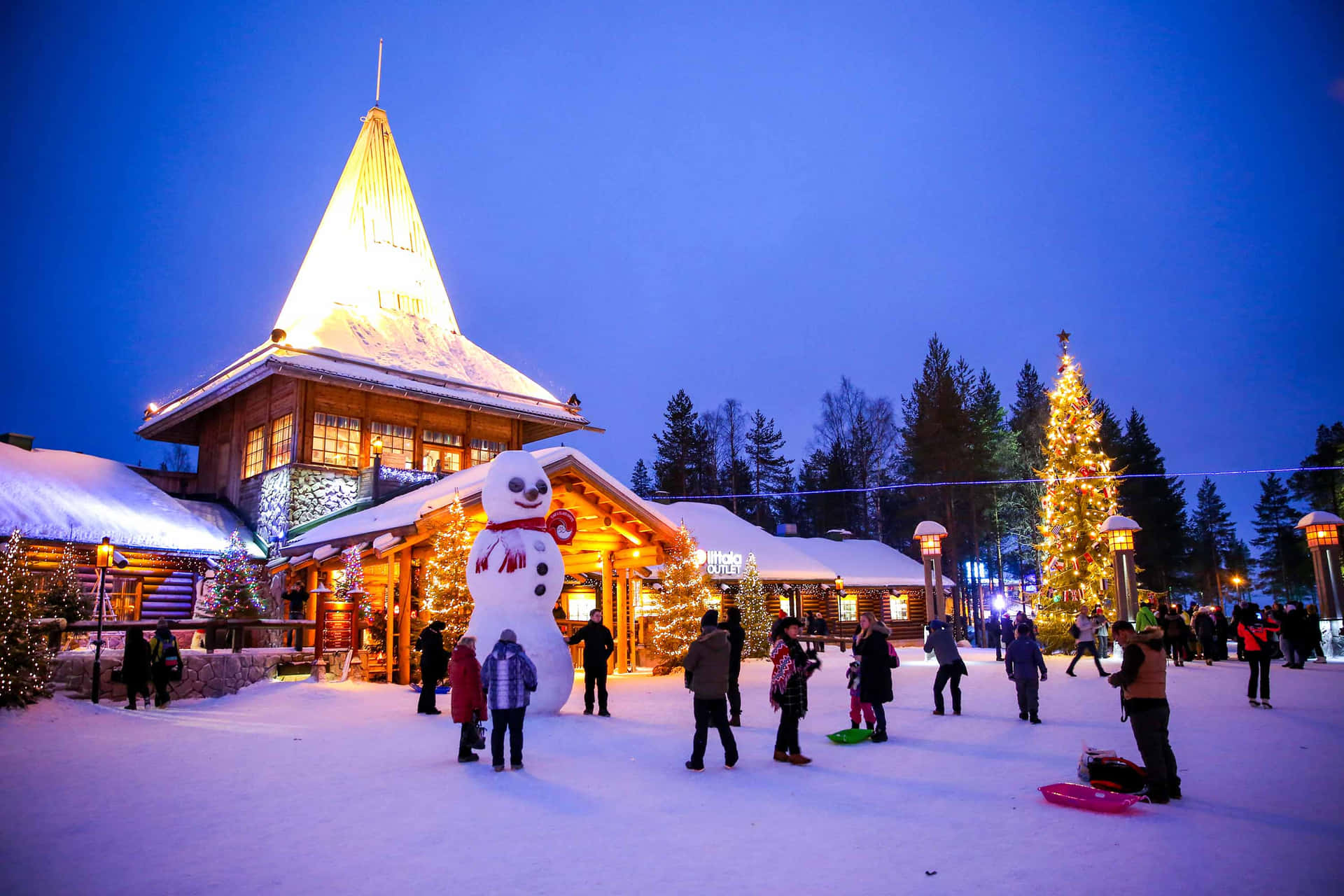 白雪覆蓋的村莊廣場，建築物燈火通明，人們享受冬日節慶。