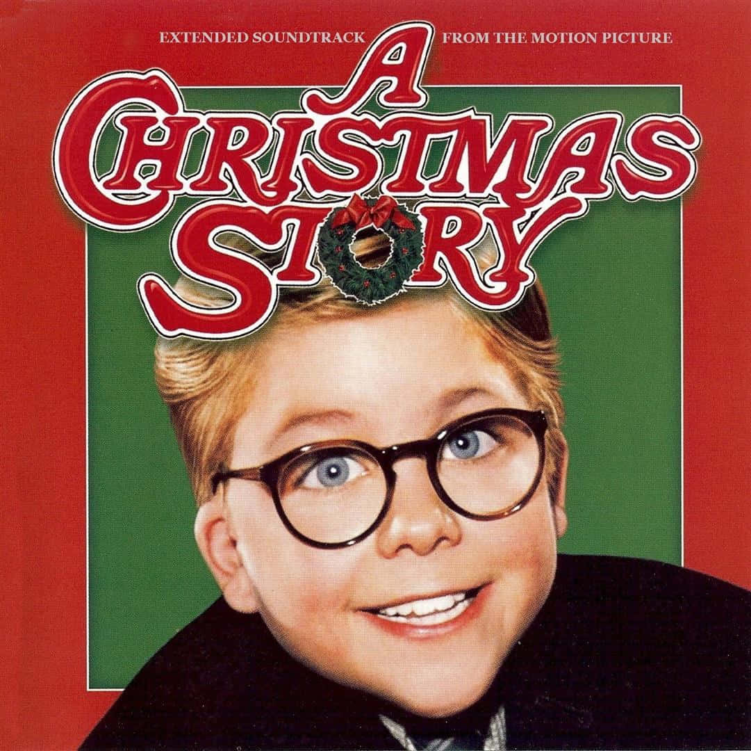 「聖誕季節唯有經典如《A Christmas Story》才能真正慶祝」 壁紙 — 一個戴著圓眼鏡的開朗小男孩，在節日紅綠背景前燦爛微笑，背景裝飾有節日文字和花環。