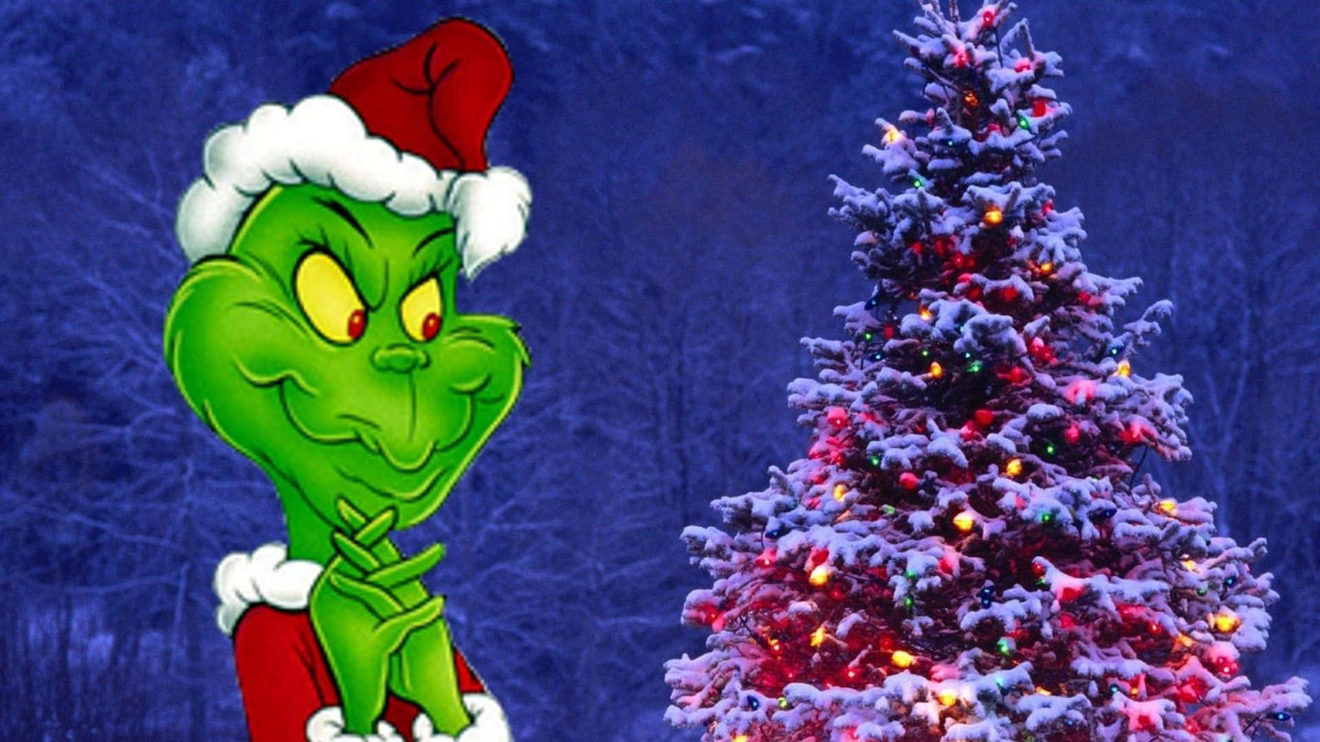 Cute Grinch 桌布 壁紙 — 聖誕怪傑戴着紅色聖誕老人帽，在黑暗的冬日樹林背景下，在掛滿彩色燈泡、積雪覆蓋的聖誕樹旁得意地笑。