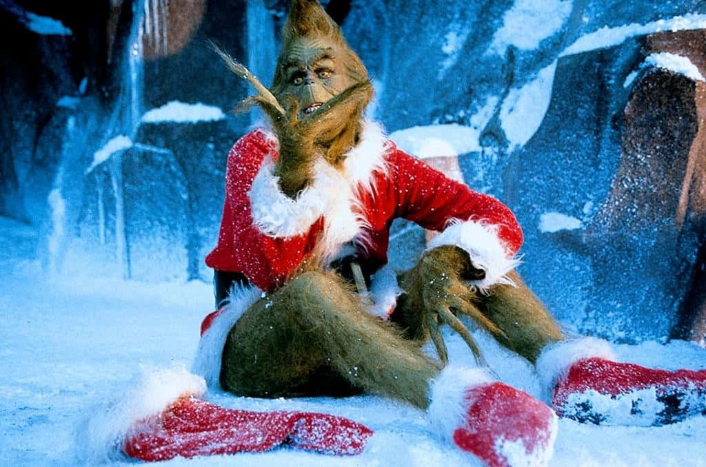 穿著紅色聖誕老人服的鬼靈精坐在雪地上，靠近冰凍岩石。