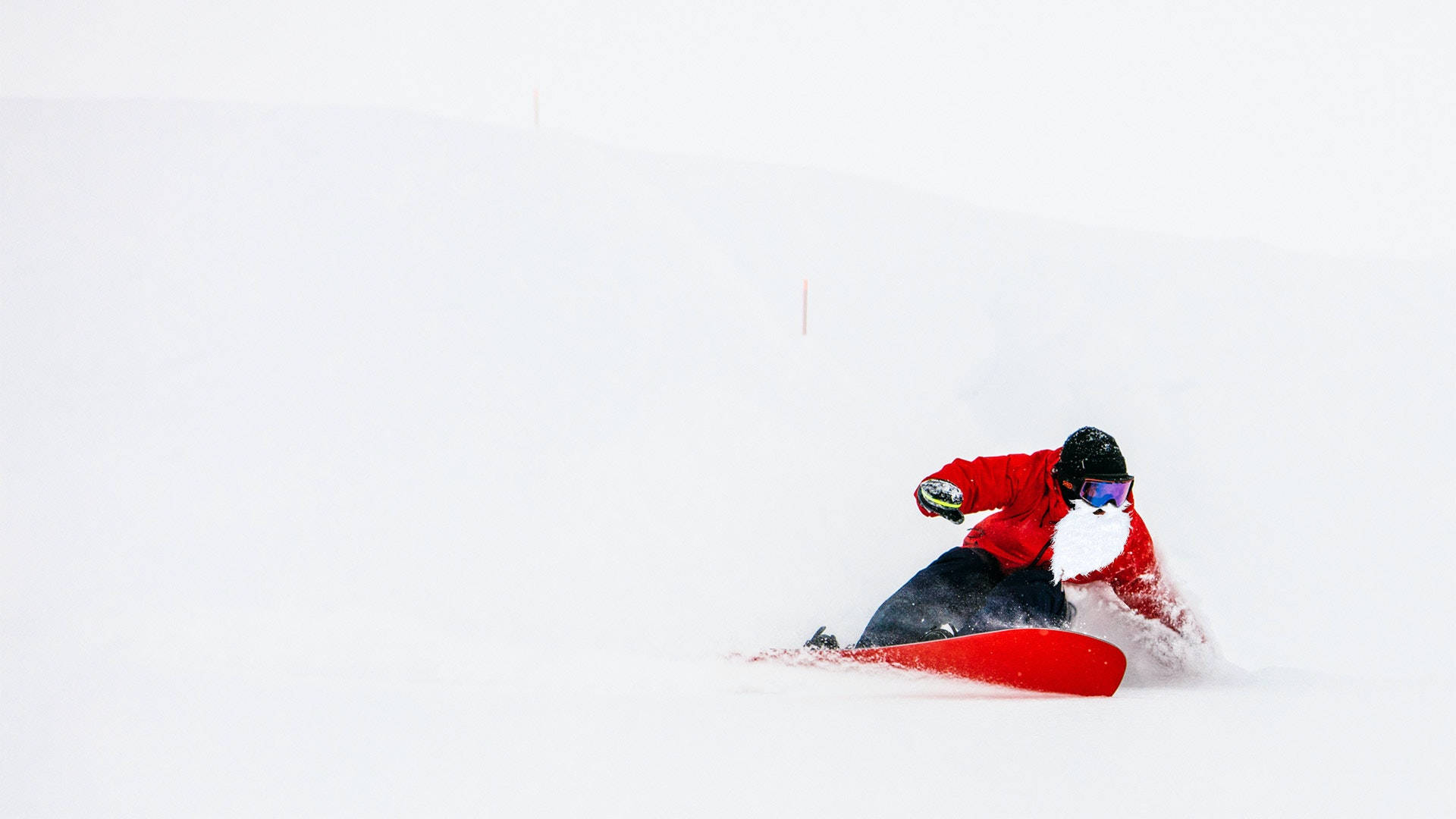聖誕老人滑雪 壁紙 — 一名身穿鮮紅色外套的滑雪板運動員在積雪的山坡上穿過深粉雪。