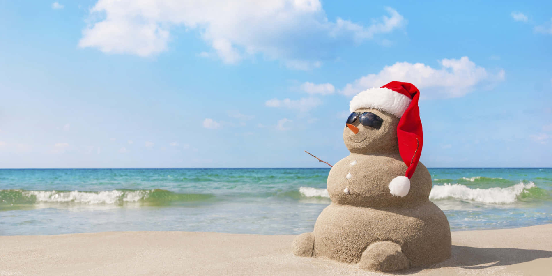 戴聖誕帽和太陽眼鏡的沙雪人，在近海的陽光海灘上。