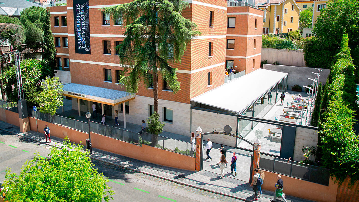 聖路易斯大學校園，學生在綠樹環繞的拱門附近行走。