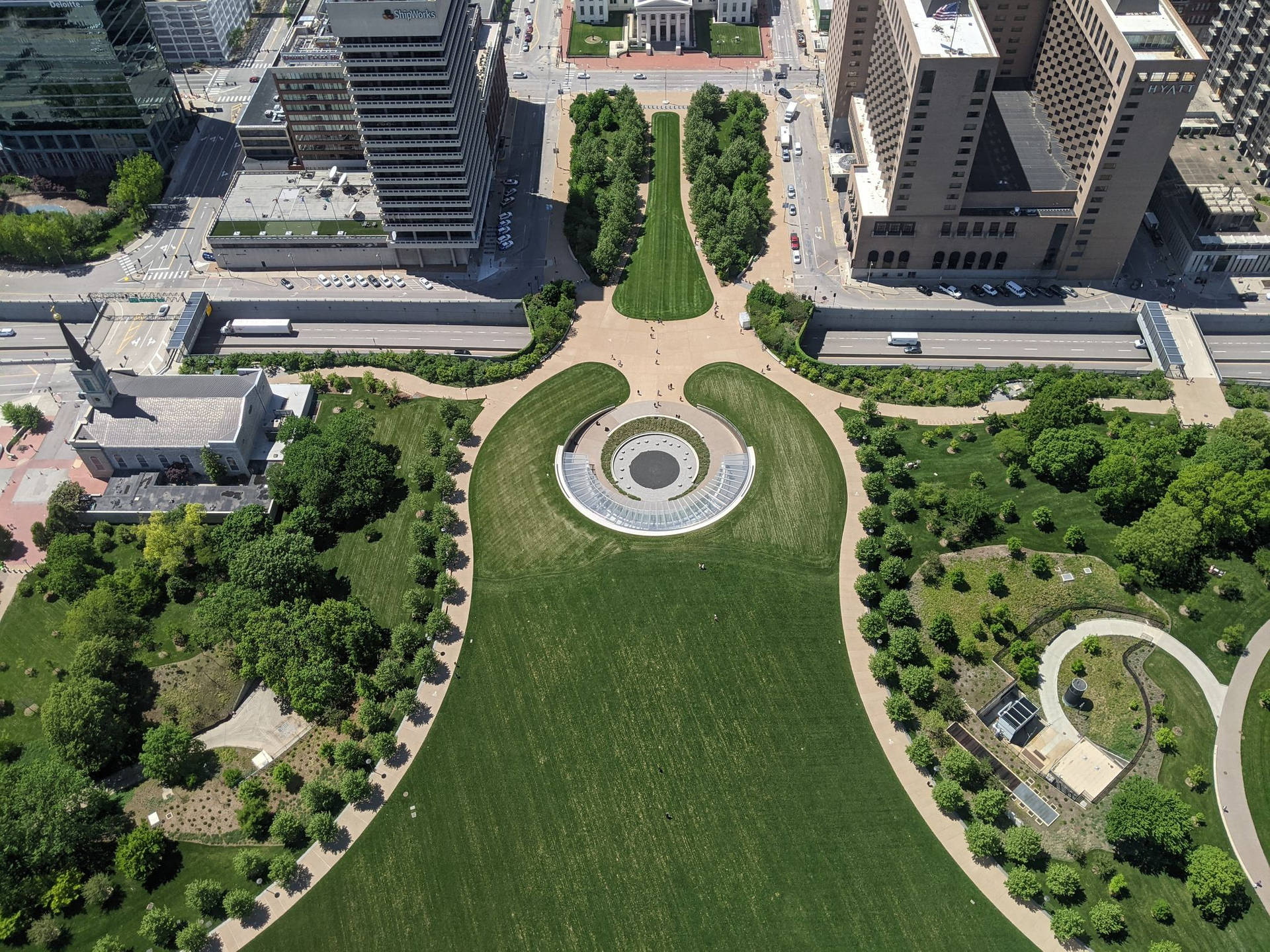綠色城市公園的鳥瞰圖，有蜿蜒小徑和現代建築。