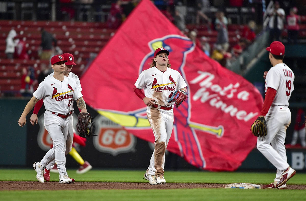 棒球運動員在球場上慶祝勝利，身後有一個巨大的紅色橫幅。