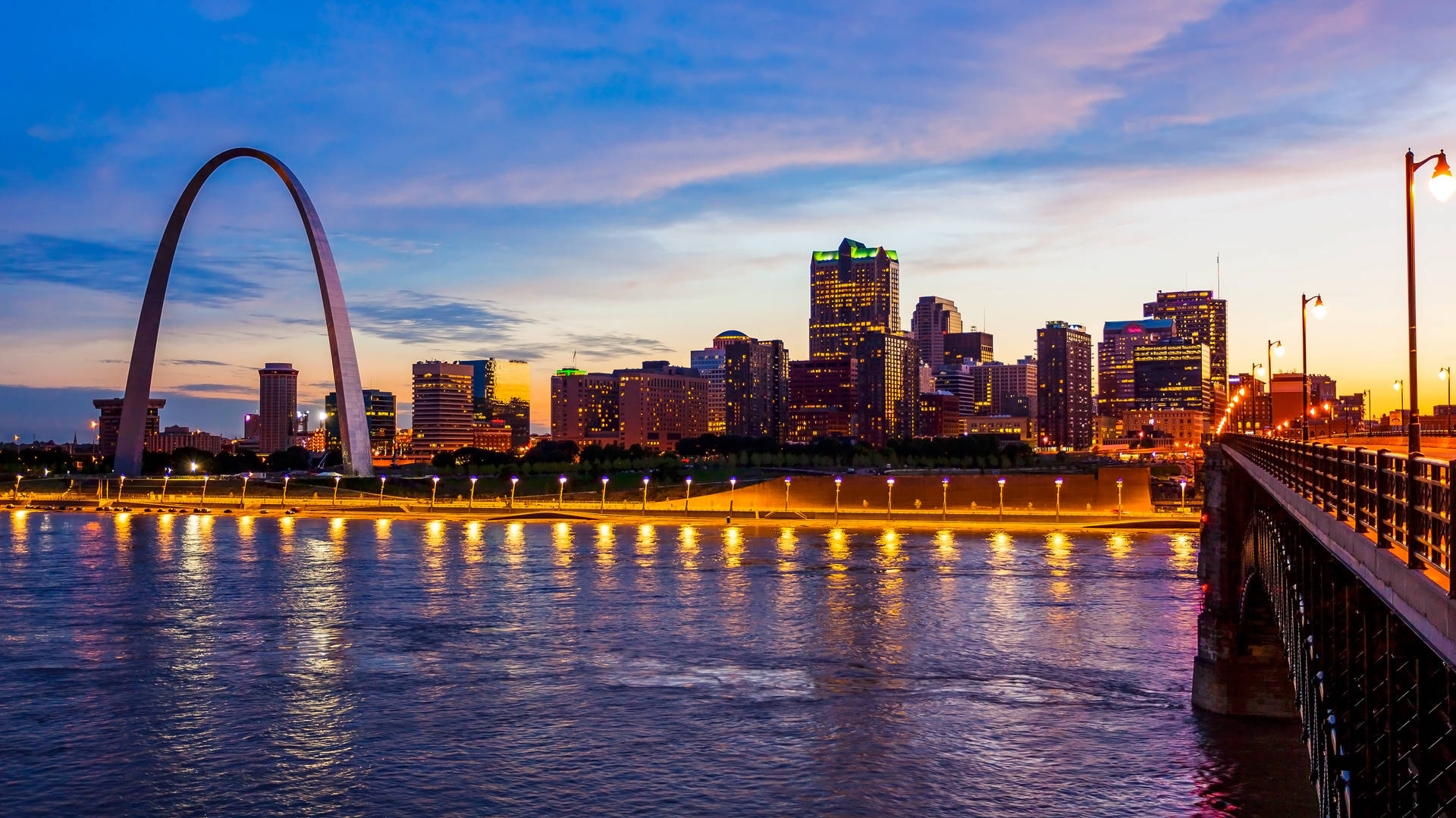 Gateway Arch 與聖路易斯日落天際線，河面倒影。