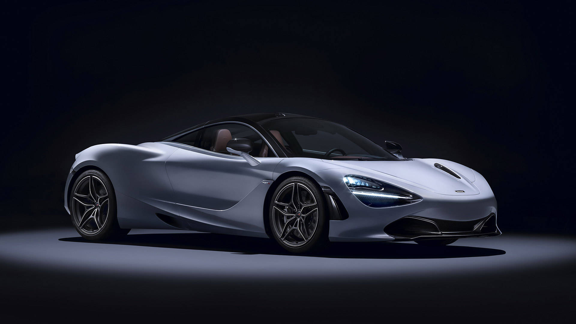 聚光燈下的4K麥拉倫720S 壁紙 — 一輛時尚的銀色McLaren 720S跑車在黑色背景下的戲劇性工作室燈光中閃耀。