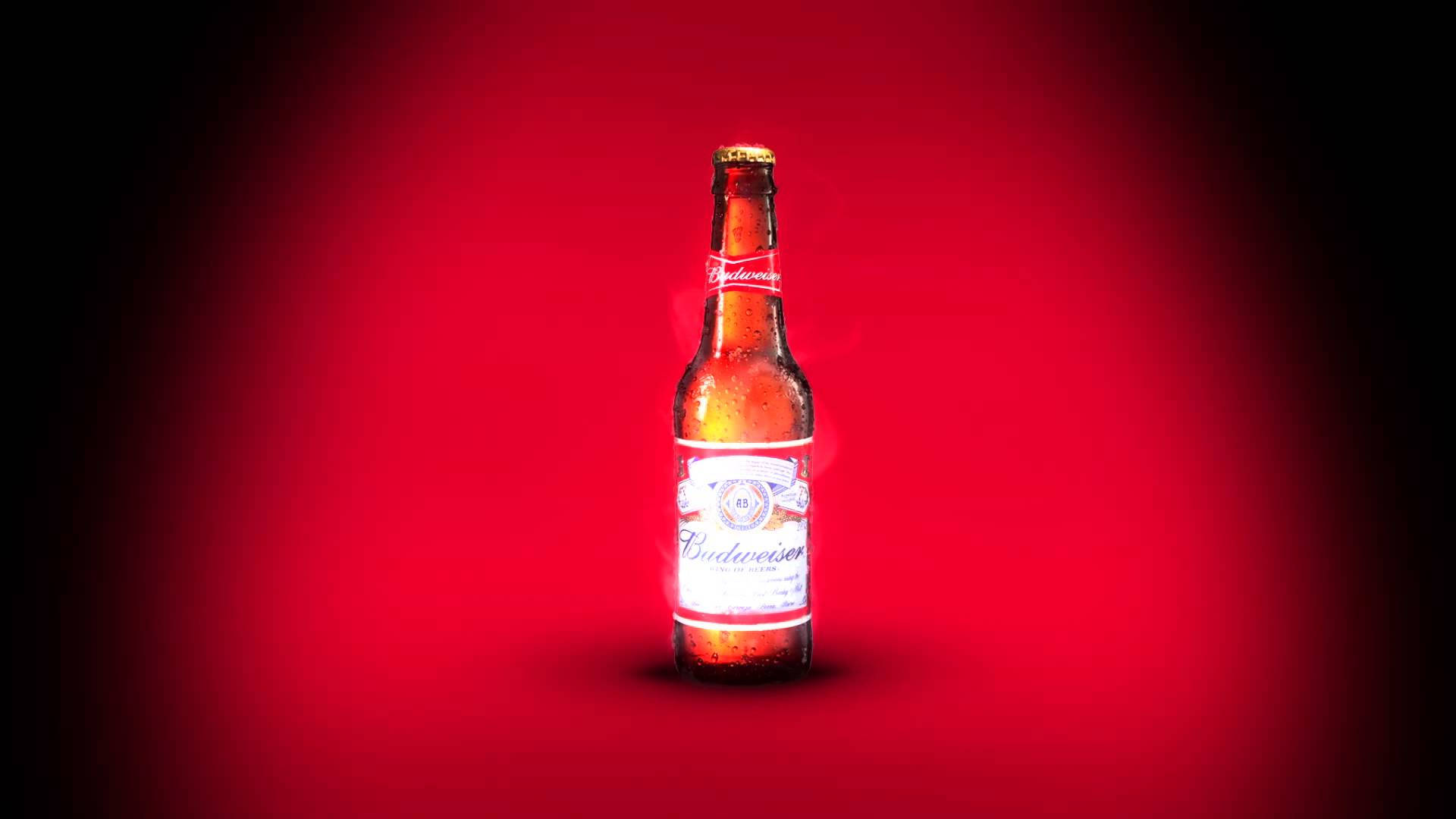 聚光燈下的百威啤酒瓶 壁紙 — 冰凍的 Budweiser 啤酒瓶在紅色漸變背景上閃爍著冷凝水珠。