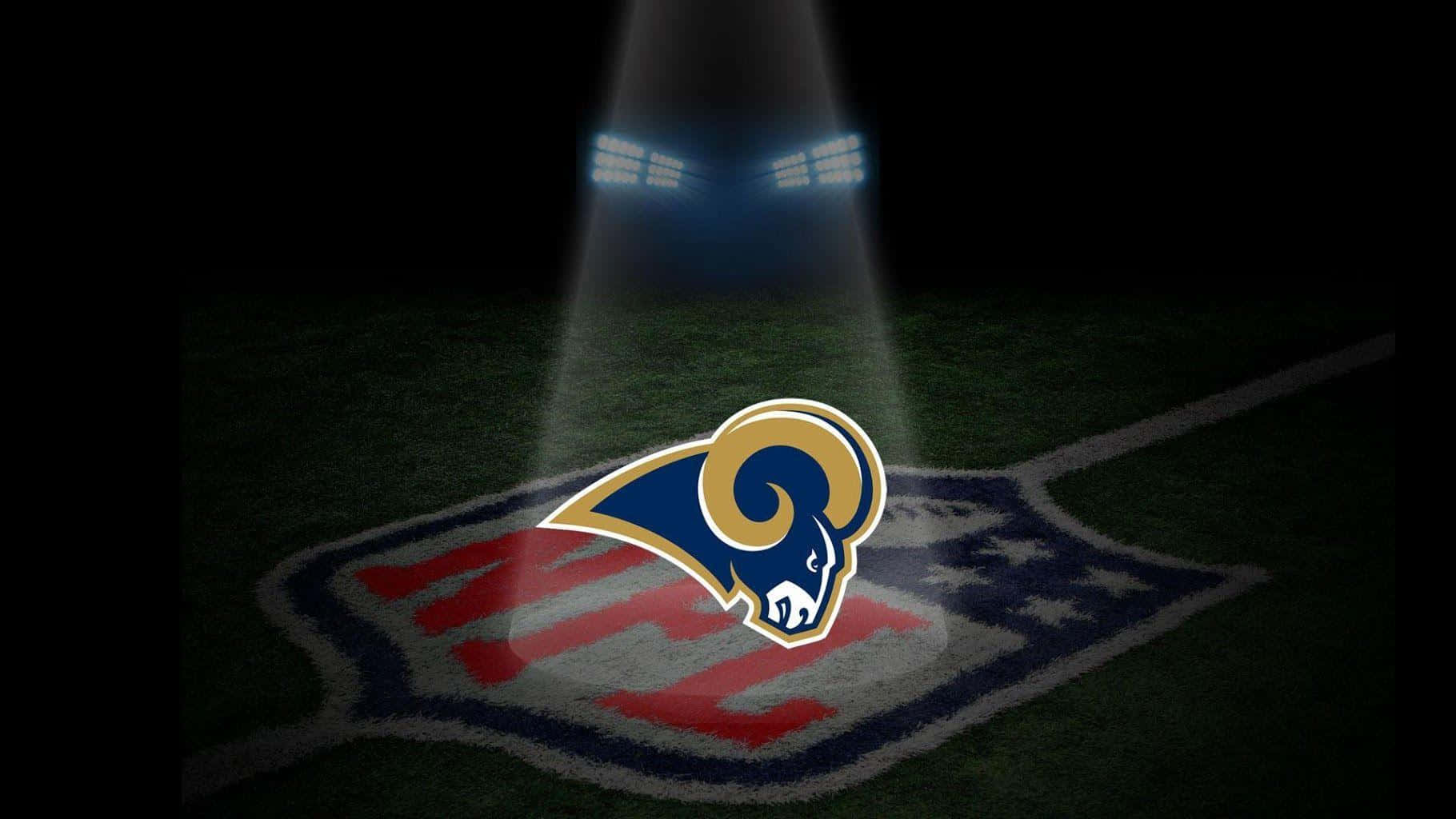 Rams 桌布 壁紙 — 聚光燈照亮了夜間NFL球場中央的洛杉磯公羊隊標誌。
