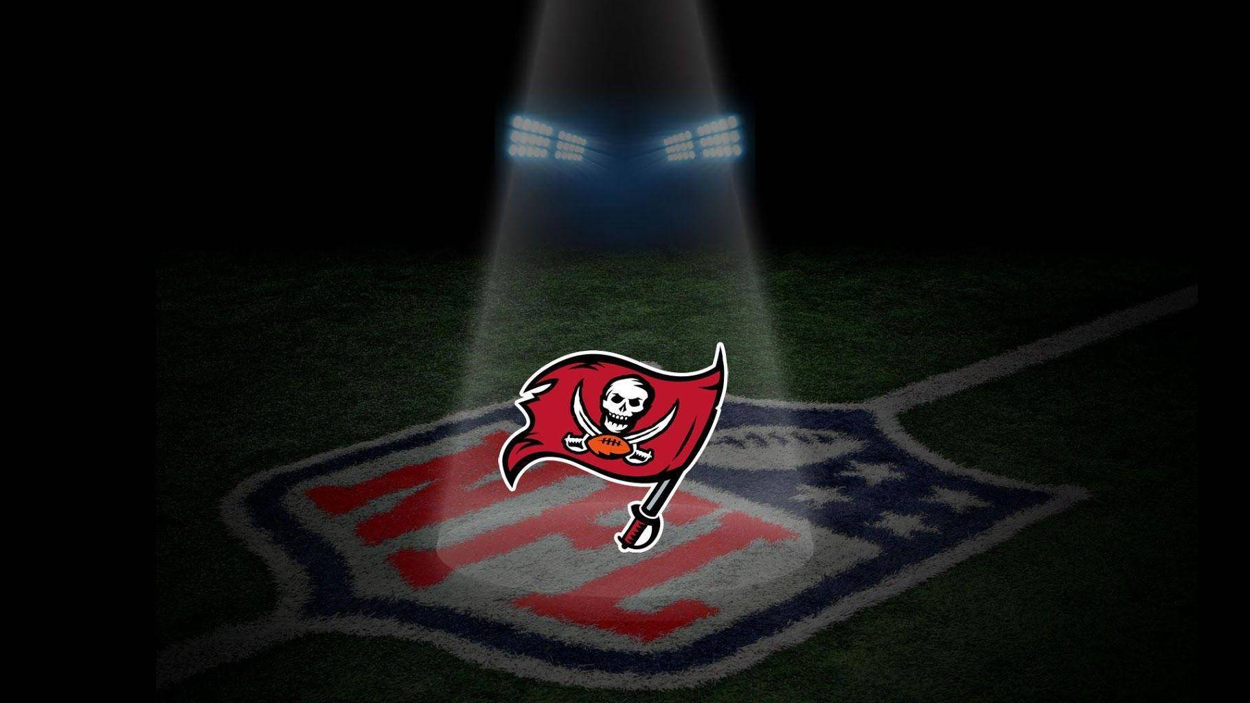 Buccaneers 桌布 壁紙 — 聚光燈照亮了夜間NFL球場中央的坦帕灣海盜隊標誌。