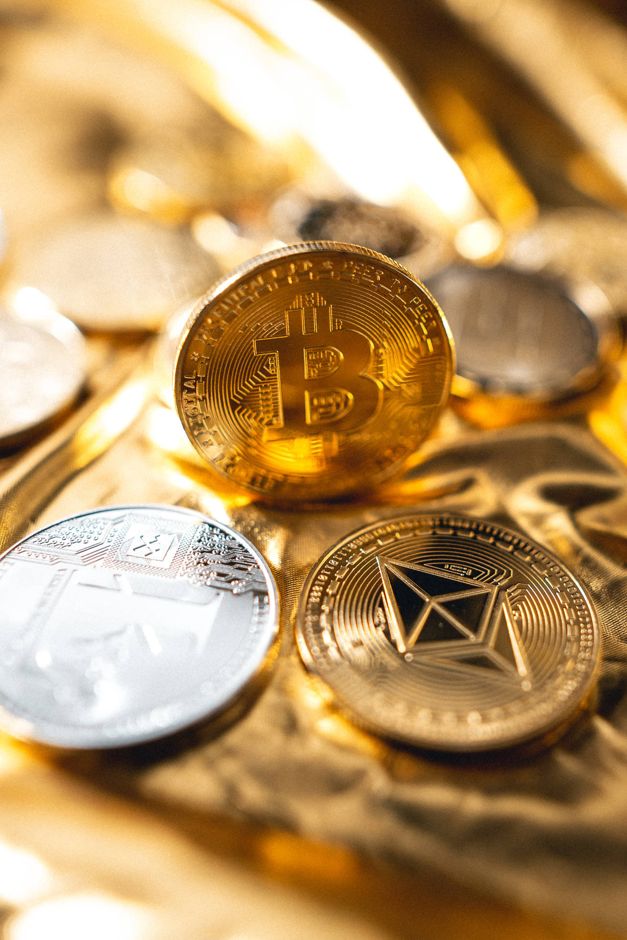堆疊在金色布料上的比特幣和以太坊加密貨幣硬幣。