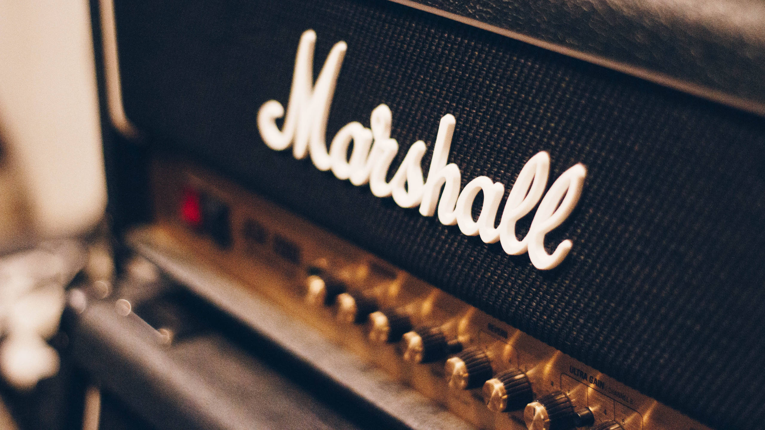 聚焦馬歇爾音箱 壁紙 — 復古Marshall結他擴音器特寫，帶有發光旋鈕和溫暖燈光。
