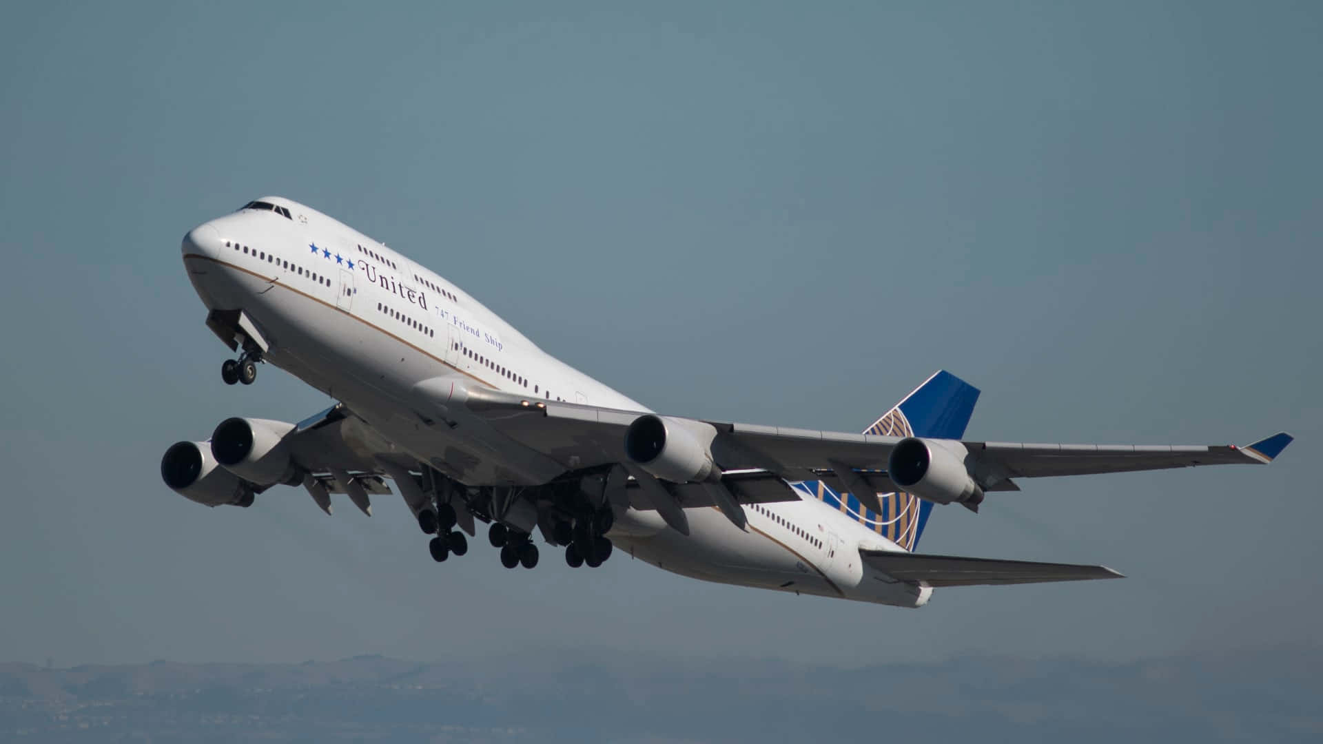 聯合航空波音747起飛，起落架放下，背景朦朧天空
