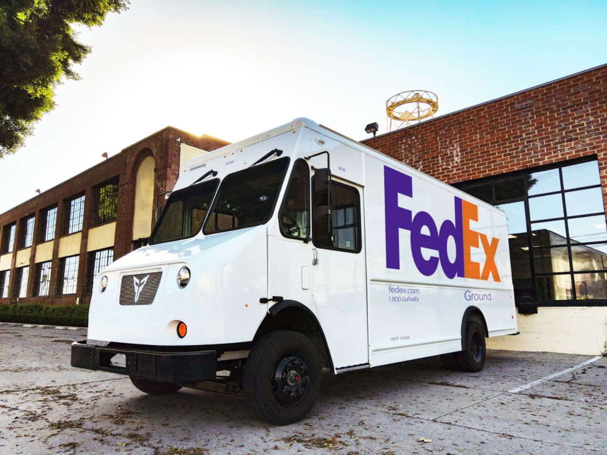 白色FedEx Ground送貨車停在磚砌建築前。