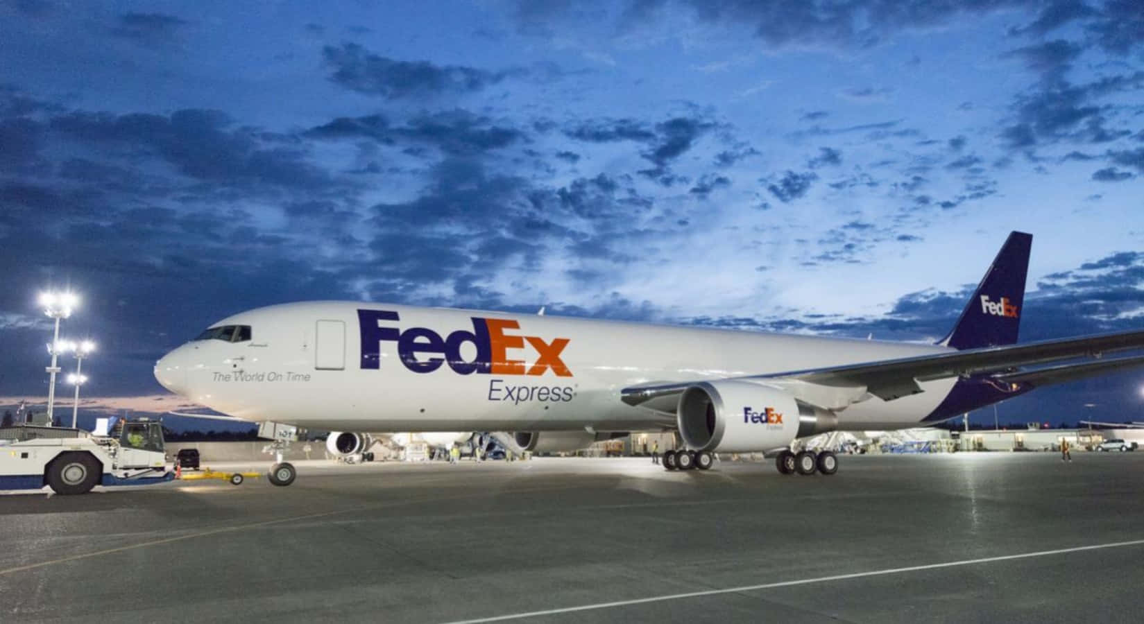 聯邦快遞貨機在暮色中停泊在機場停機坪，地面燈光亮起。