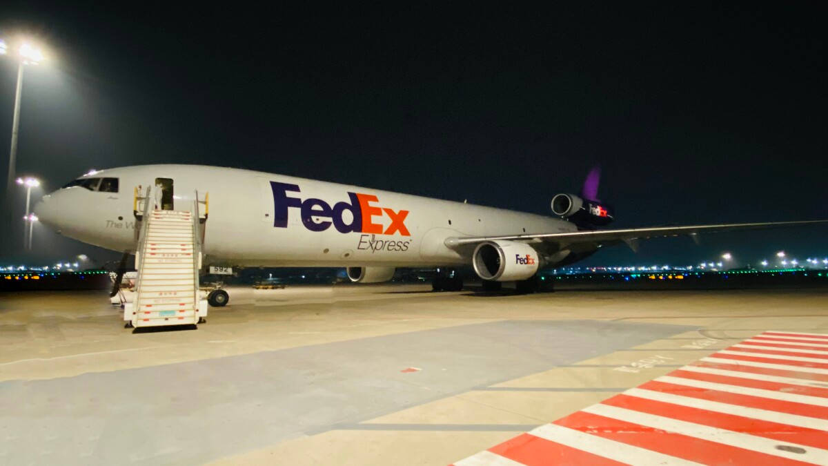 聯邦快遞貨機夜間停在機場停機坪，附有登機梯和跑道燈。