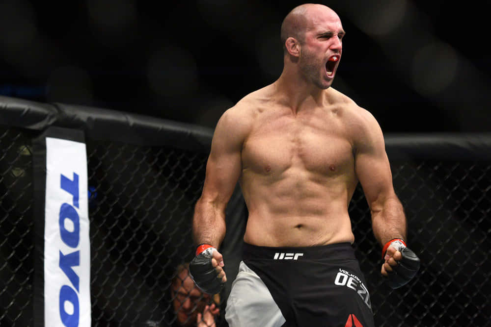 一位赤裸上身的MMA鬥士在UFC八角籠內慶祝勝利。